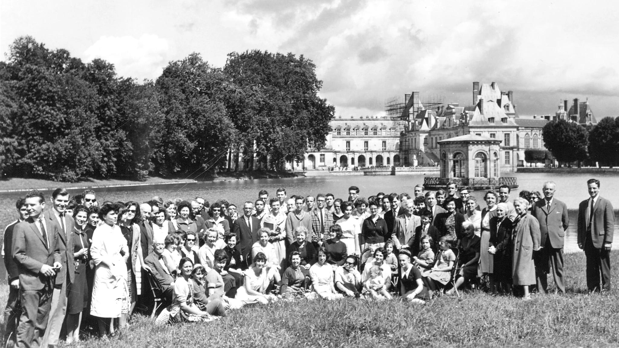 Ett stort antal människor står samlade vid en sjö framför slottet i Fontainebleau. De sitter i gräset och står utspridda så att alla ska synas på fotot.