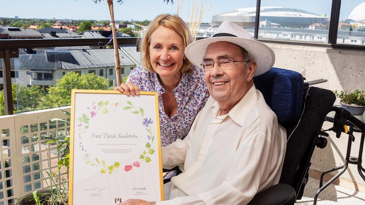 Sven-David Sandstöm och Bibi Rödö. Sven-David håller upp ett diplom för sin medverkan i Sommar i P1.