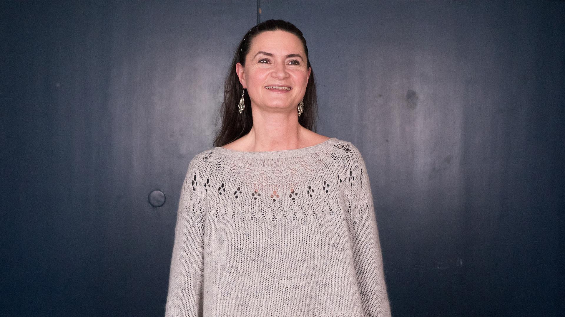 Christiane Højlund, Radiokören. Kvinna med långt mörkt hår som ler stort och tittar lite åt sidan. Hon har stora hängande silverörhängen och en grå stickad tröja.