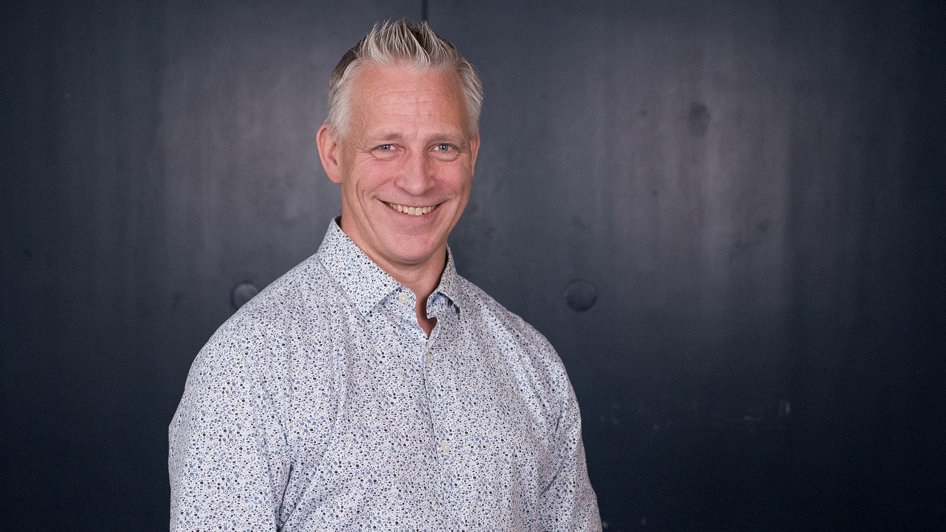 Gunnar Sundberg, Radiokören. Glad man med grått kortklippt hår tittar in i kameran. Han har en ljus skjorta med många små prickar i olika blå nyanser.