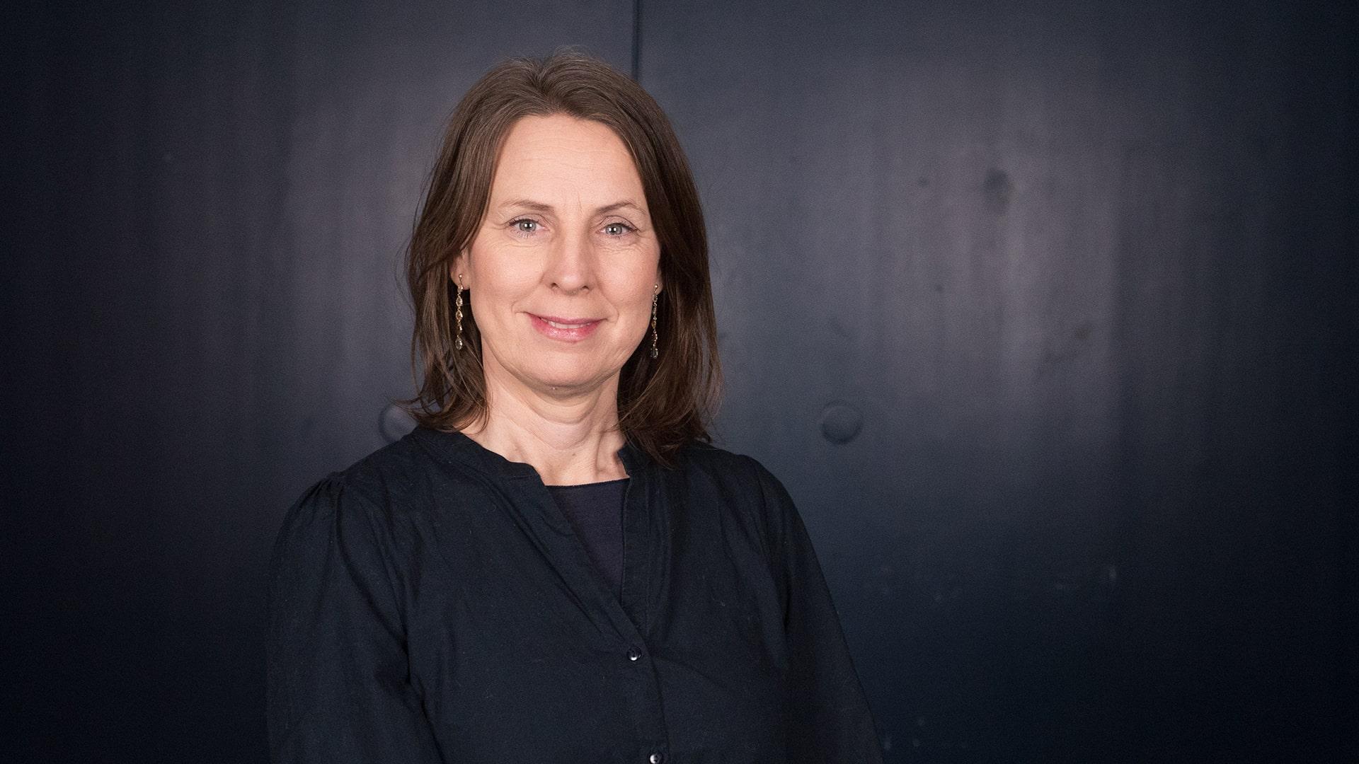 Jennie Eriksson, Radiokören. Kvinna i svart blus tittar leende in i kameran. Hon har långt brunt hår och hängande örhängen.