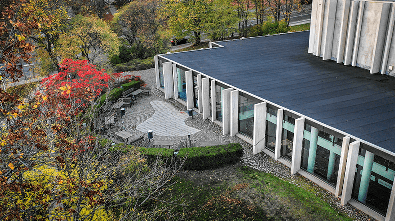 En drönarbild över Berwaldhallens exteriör, med omkringliggande grönska som skiftar i höstens färger.