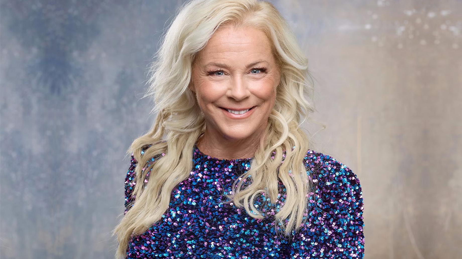 Sångerskan Malena Ernman ler och tittar rakt in i kameran. Hon har en blå glittrig klänning på sig.