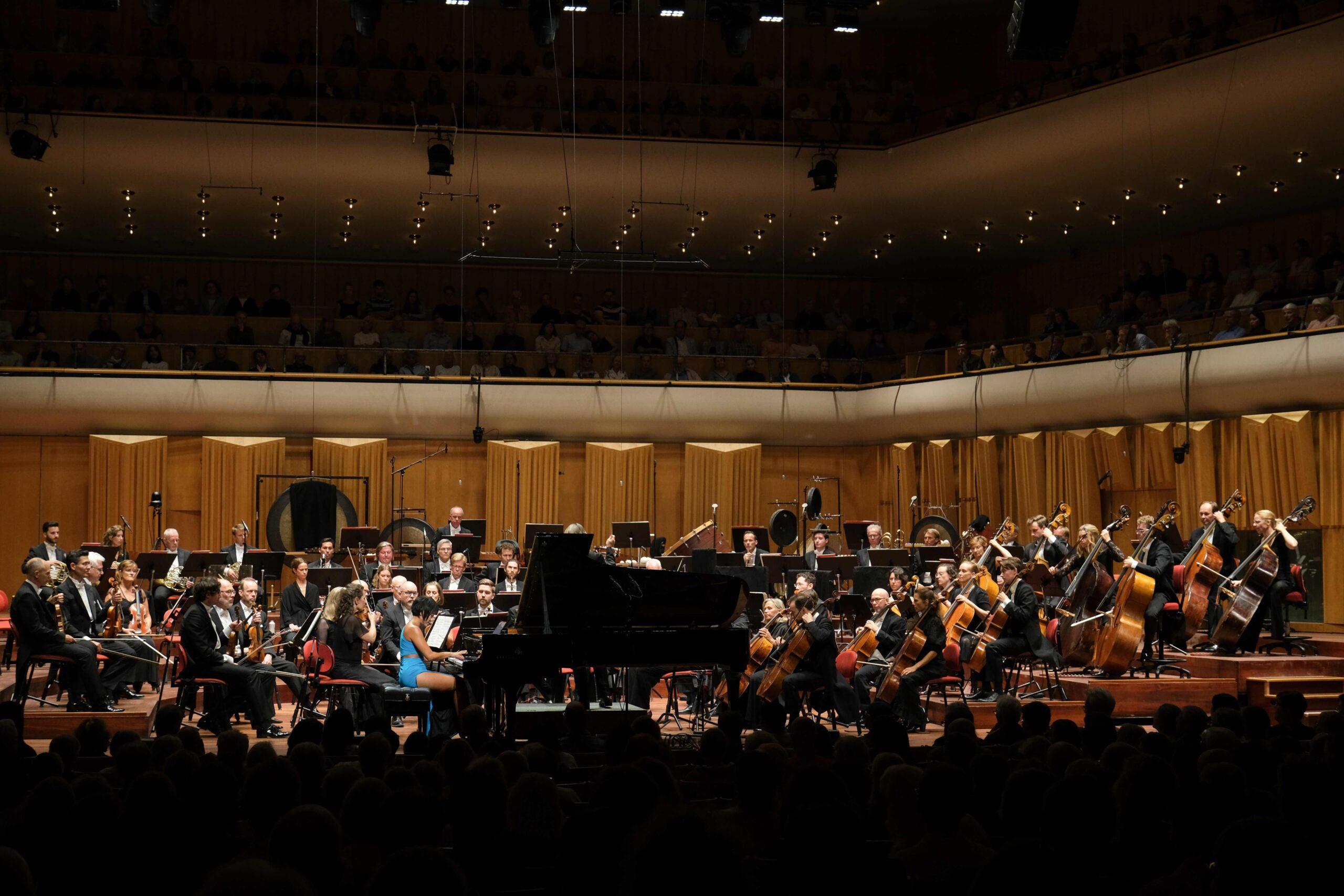 Ett foto på en pianist vid en flygel framför en symfoniorkester