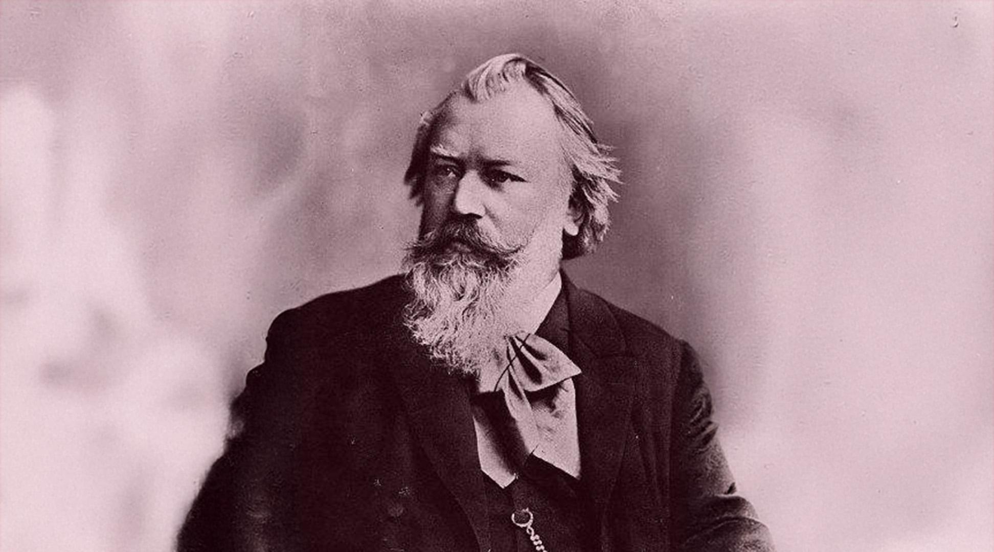 Porträtt av Johannes Brahms. Han har halvlångt hår, mustasch och skägg. Mörk kavaj.