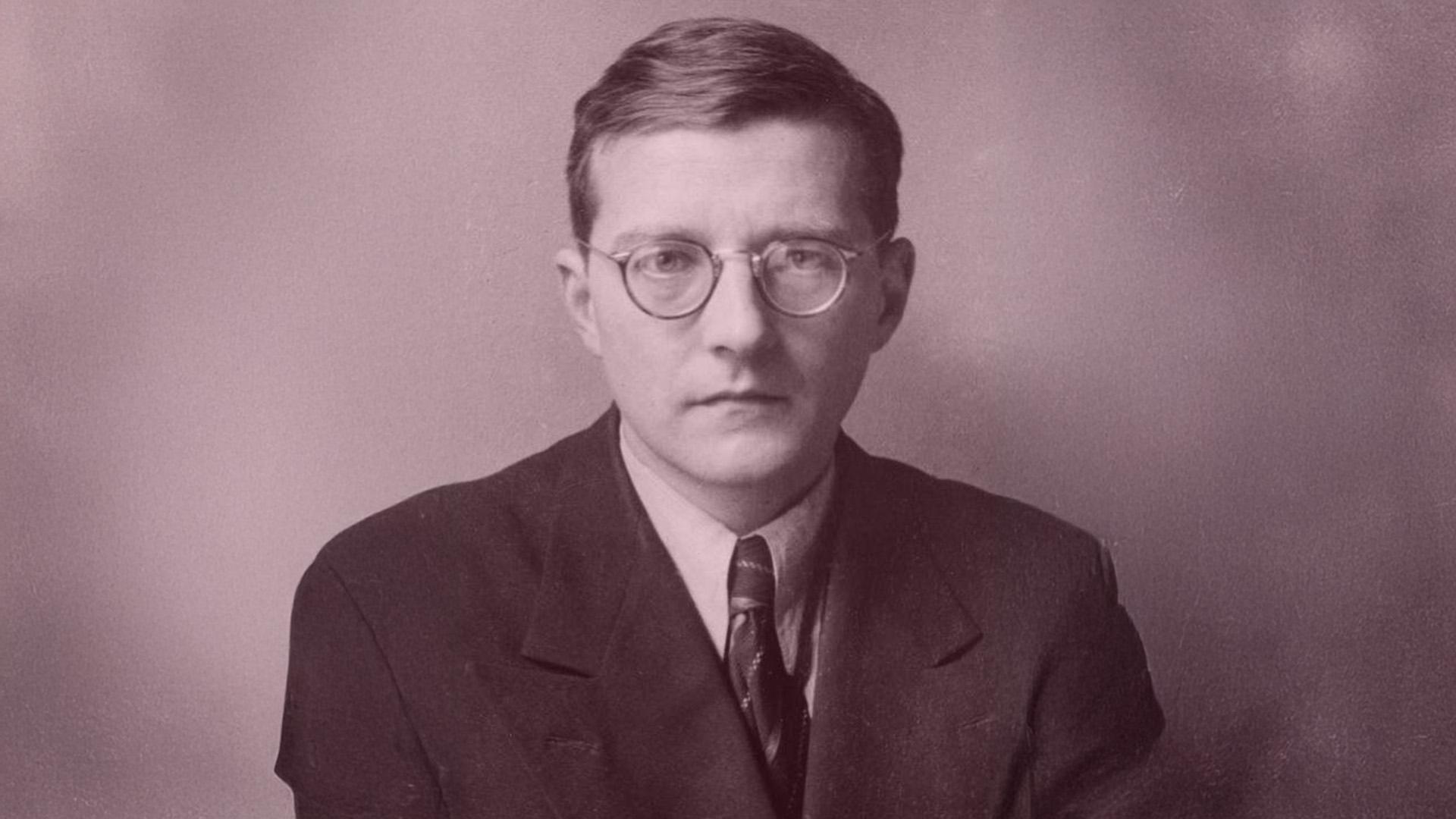 Porträttbild av Dmitrij Sjostakovitj med runda glasögonm mörk kavaj, ljus skjorta och slips. Allvarsam min.